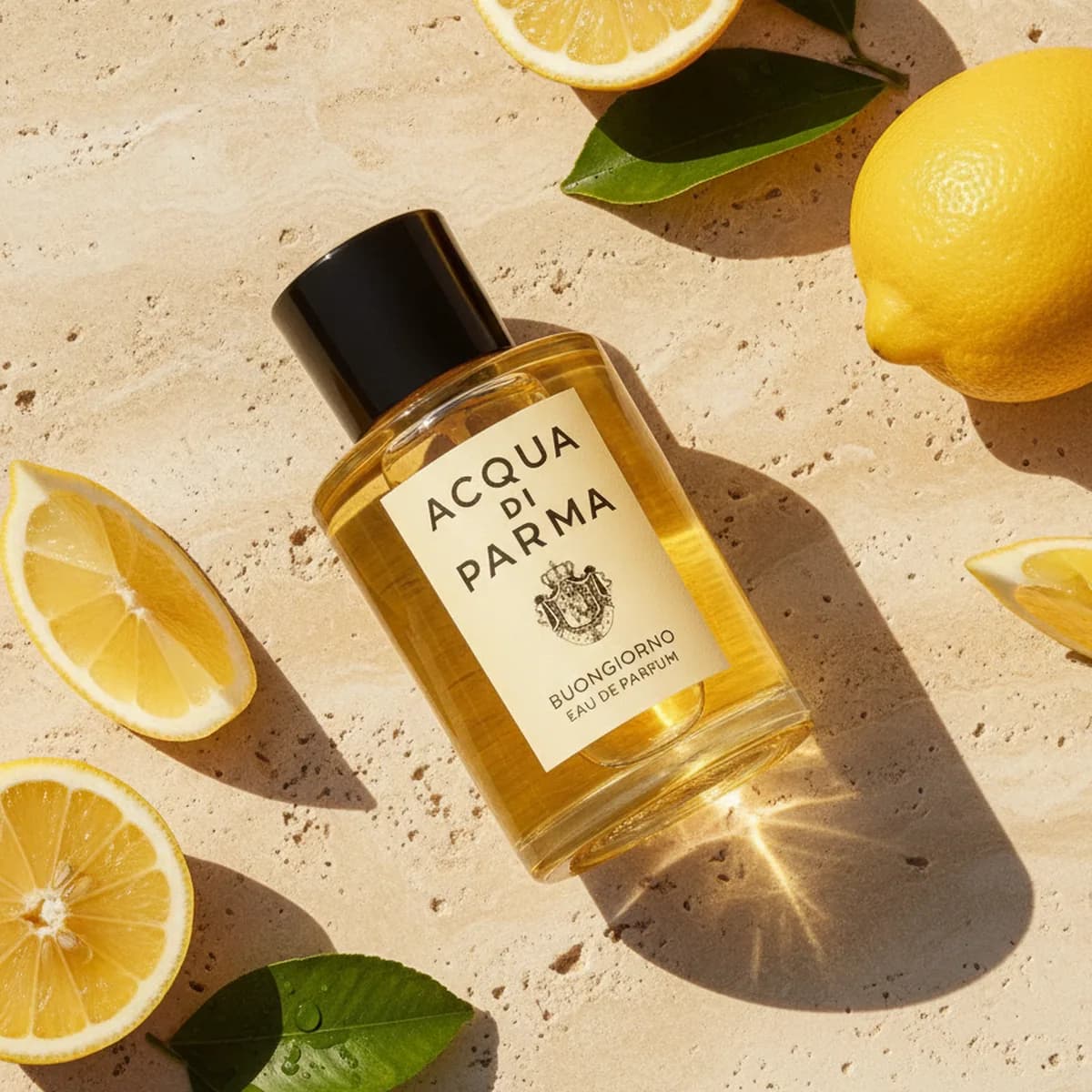 A bottle of Acqua di Parma on sunlit stone among cut lemons and leaves