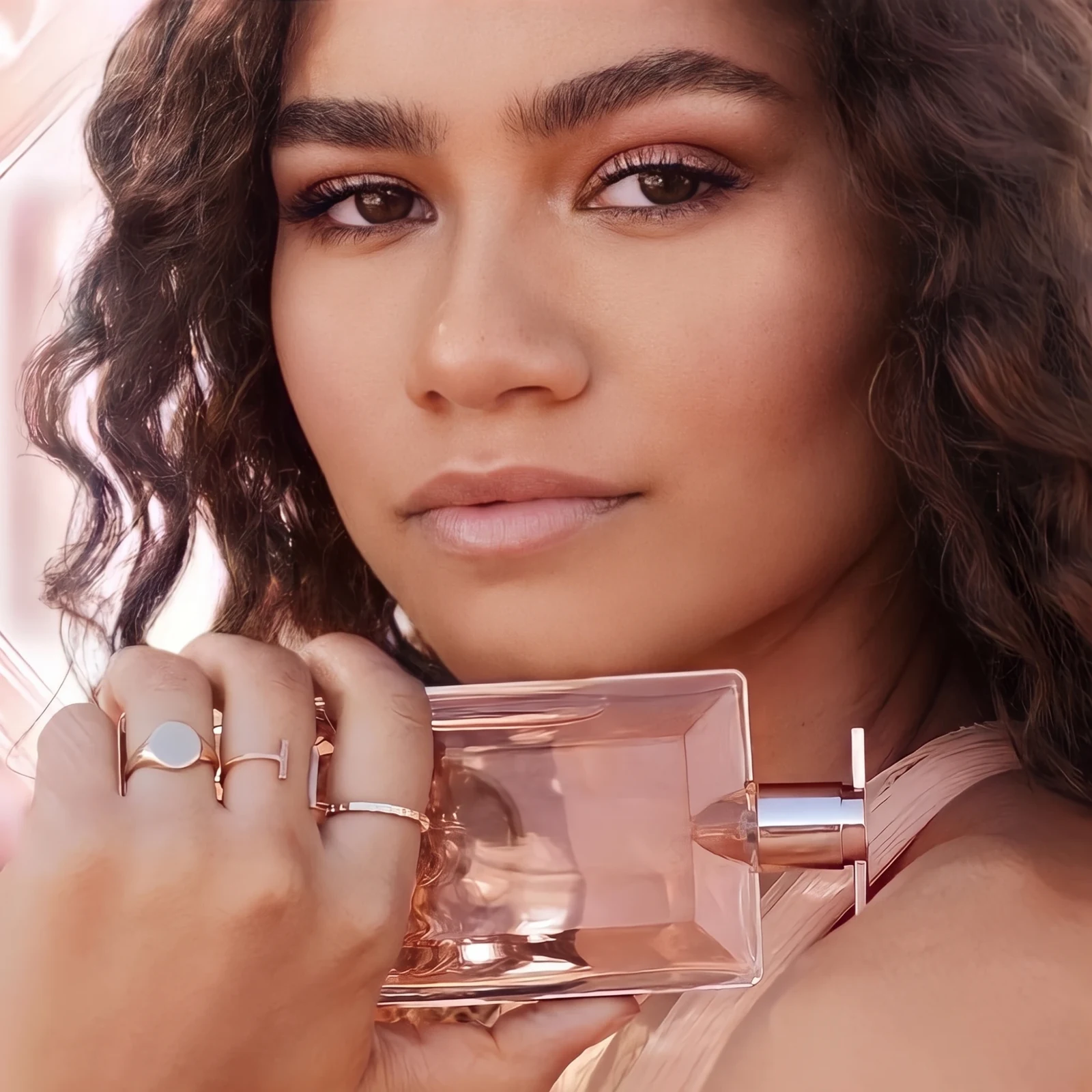 A woman holding a bottle of Lancôme Idôle against her shoulder